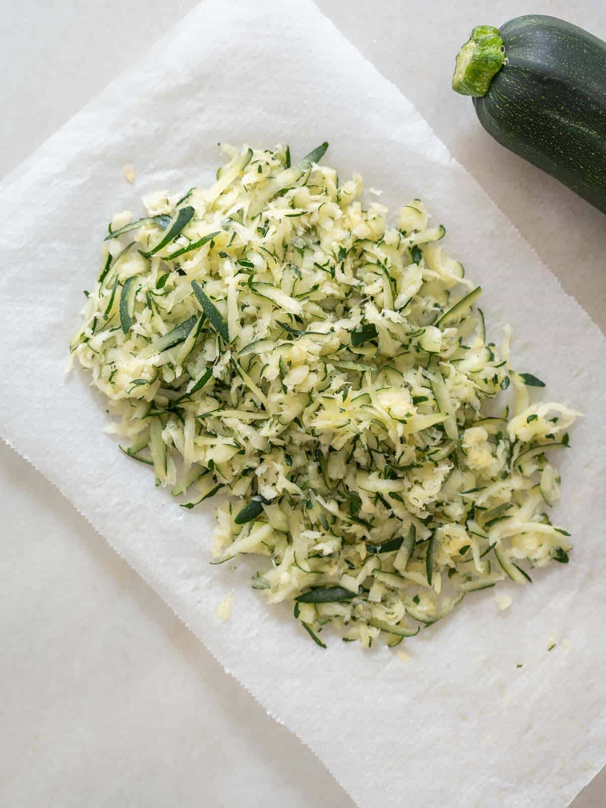 shredded zucchini laying on parchment paper.