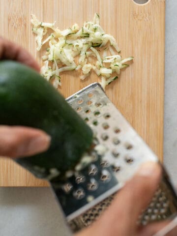 shredding zucchini using a cheese grater.