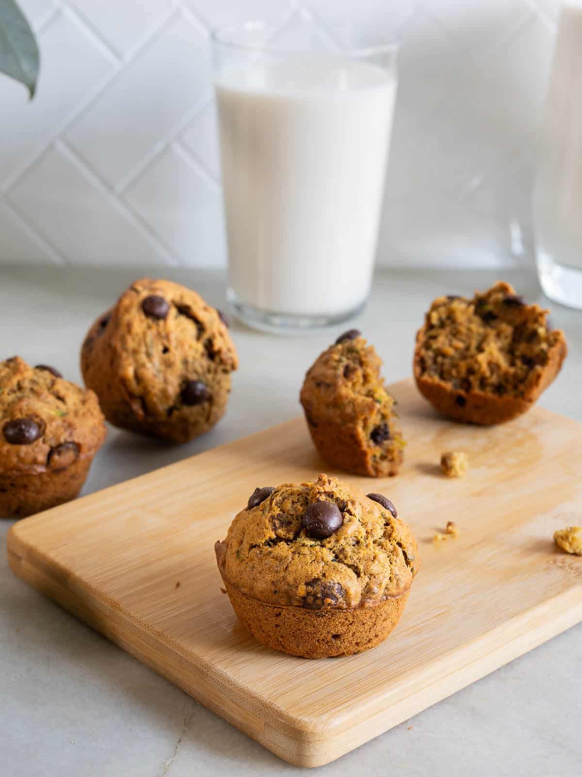 vegan zucchini muffins on a wooden table with a glass of almond milk.