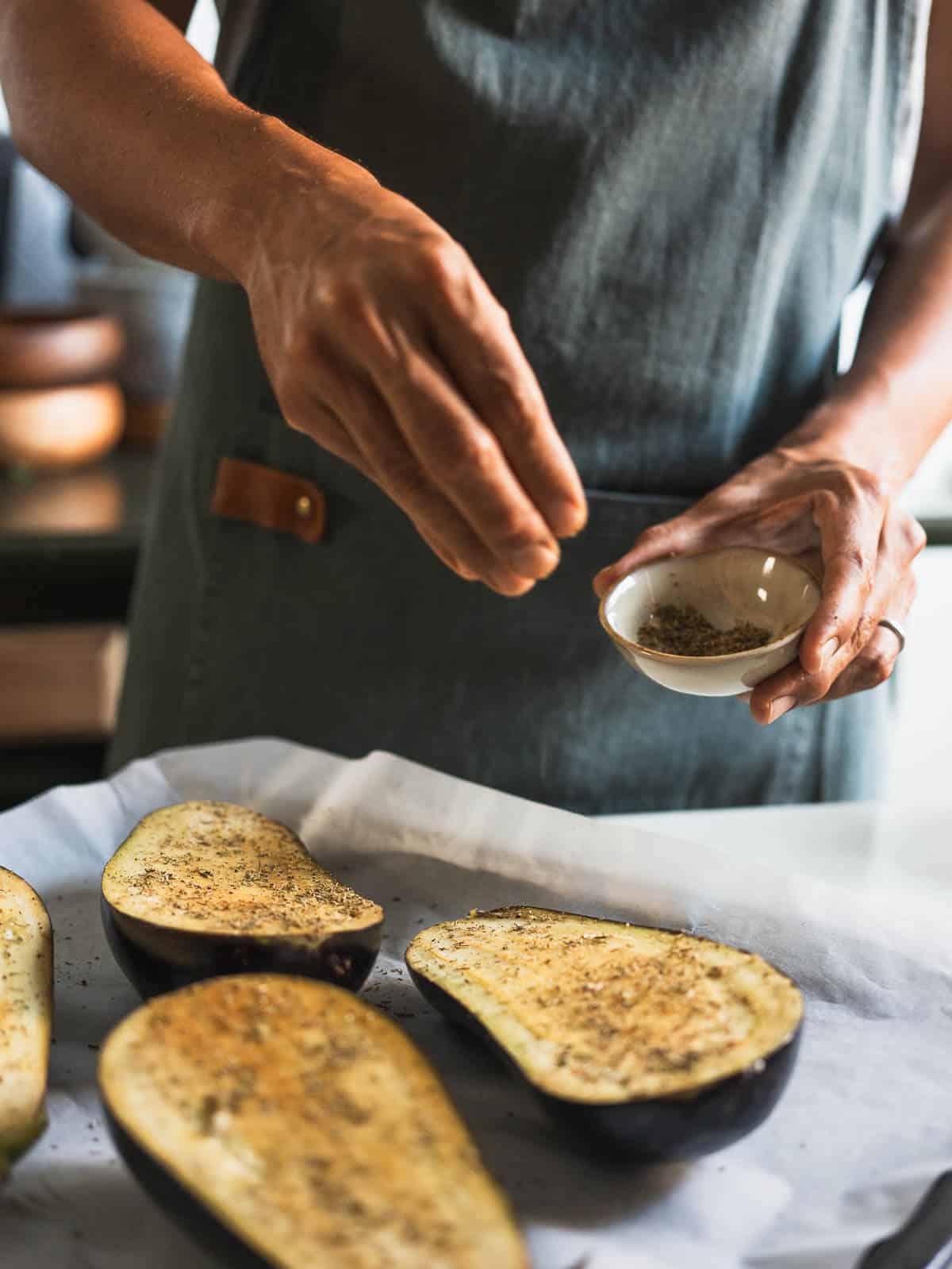 sprinkling salt and pepper over eggplants.