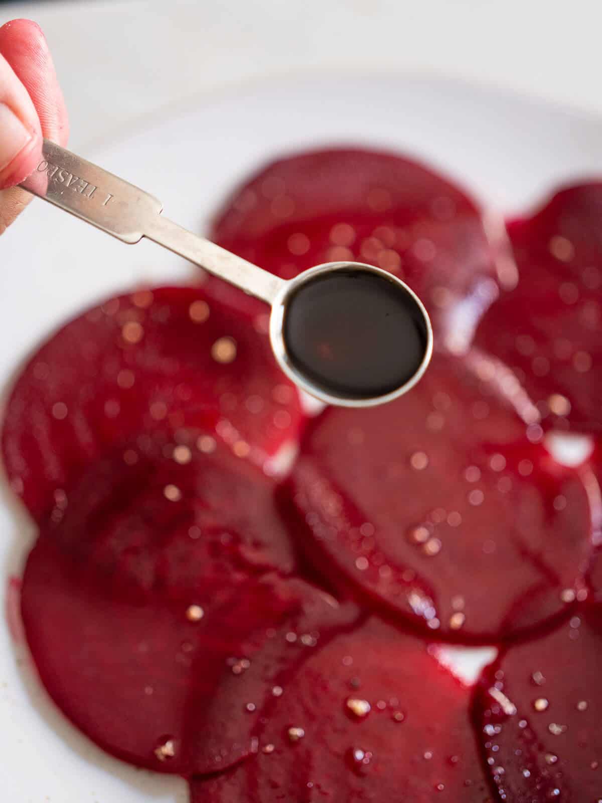adding balsamic vinegar, salt and pepper to the layer or thinly sliced beets.