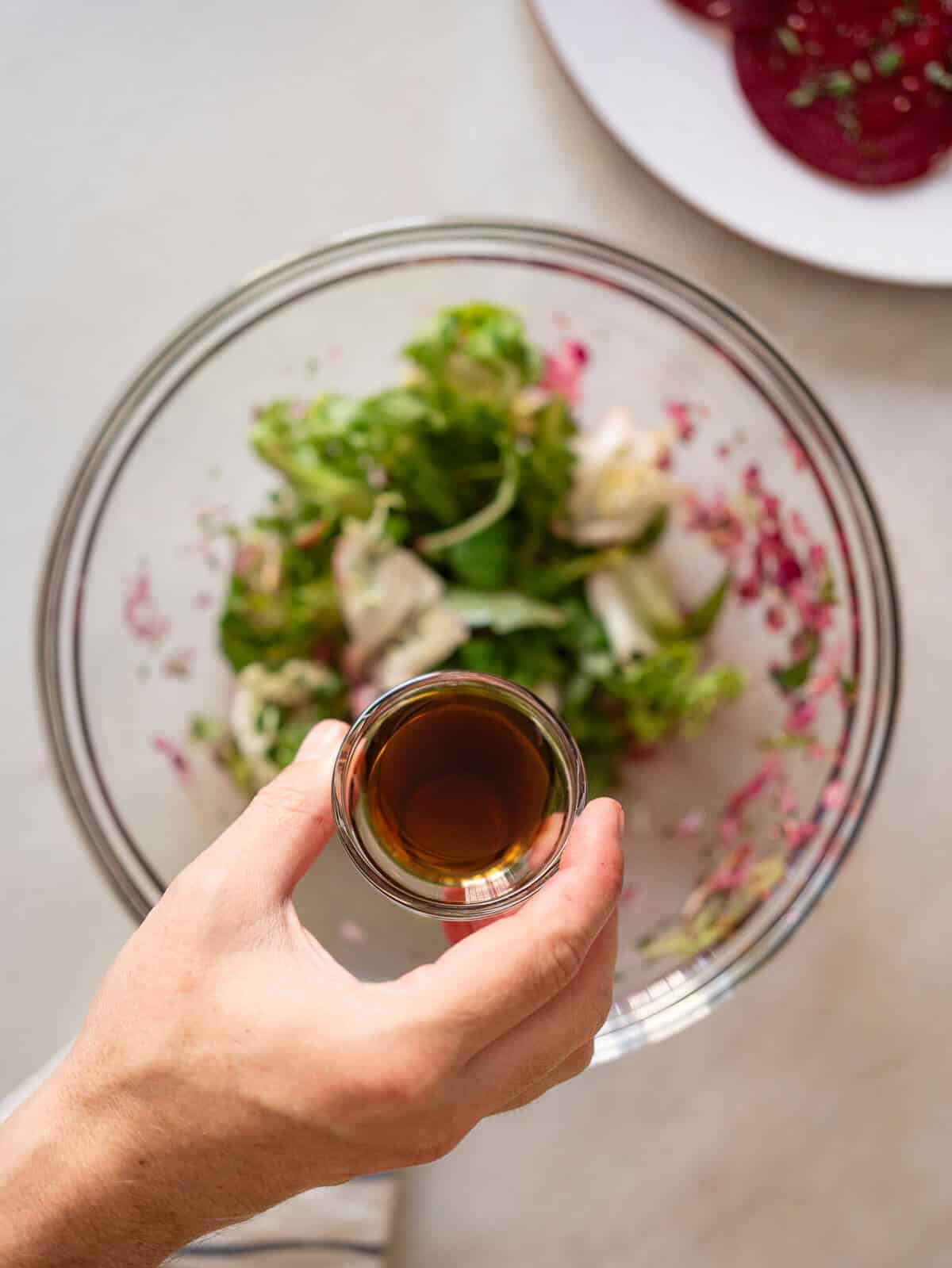 adding balsamic vinegar to the greens bowl.