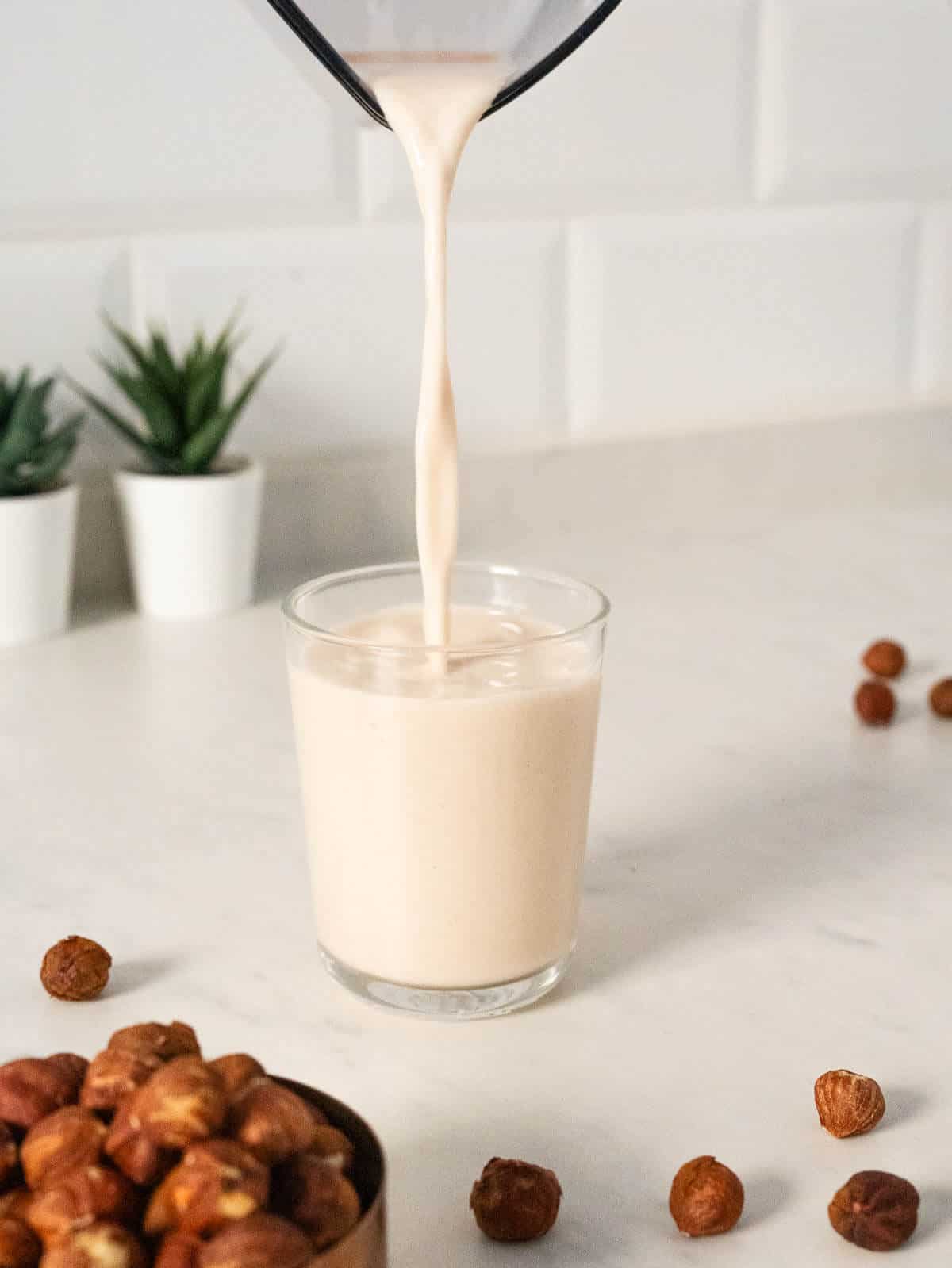 pouring creamy hazelnut milk into a glass.