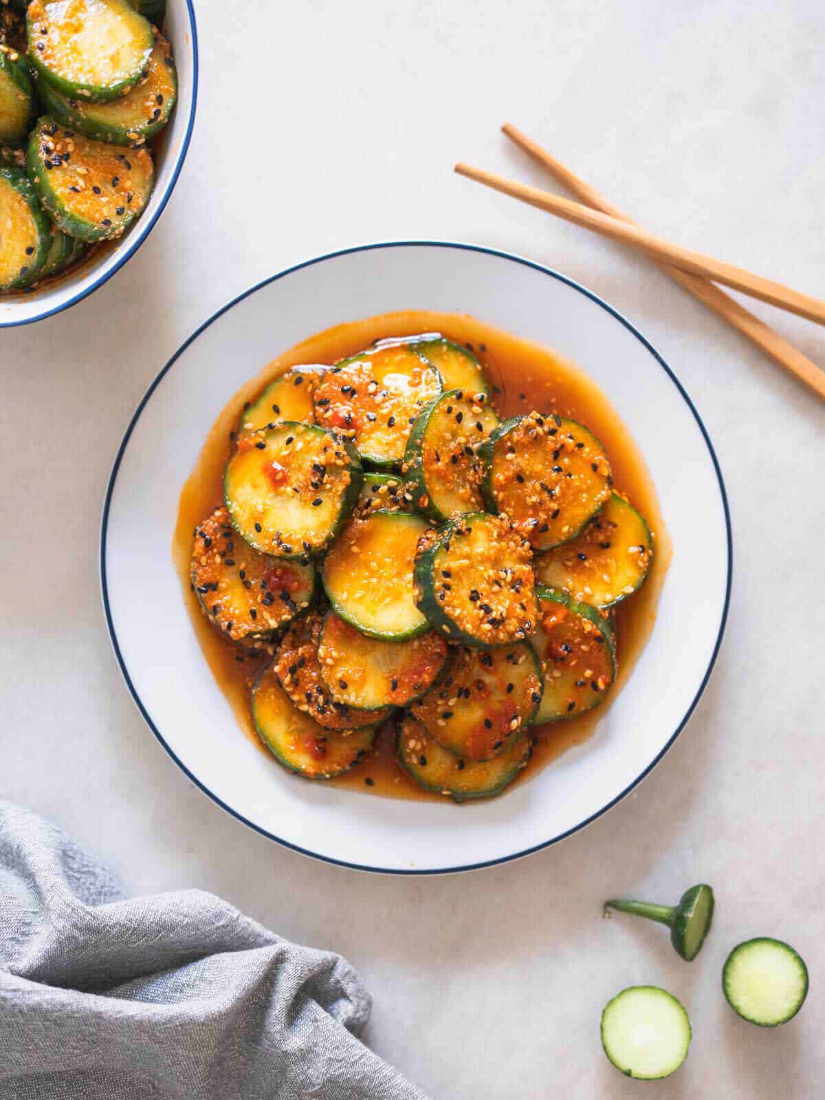 spicy Korean cucumber salad served in a white plate with chopsticks.