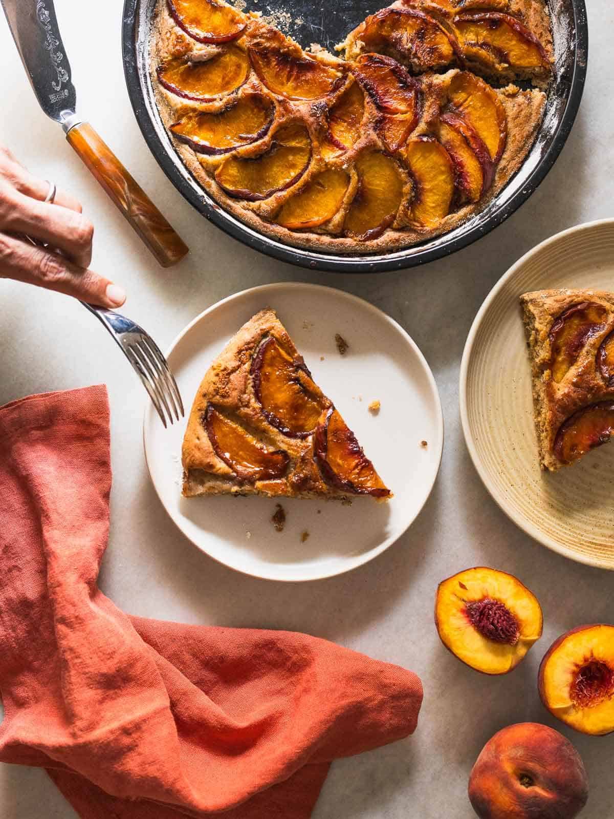 brown sugar peach cake slices served in two plates next to the baking dish.