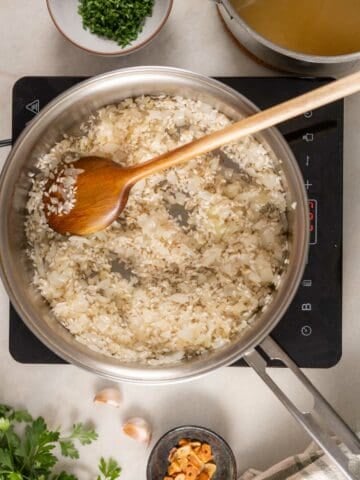 adding arborio rice to the sautéed onions.