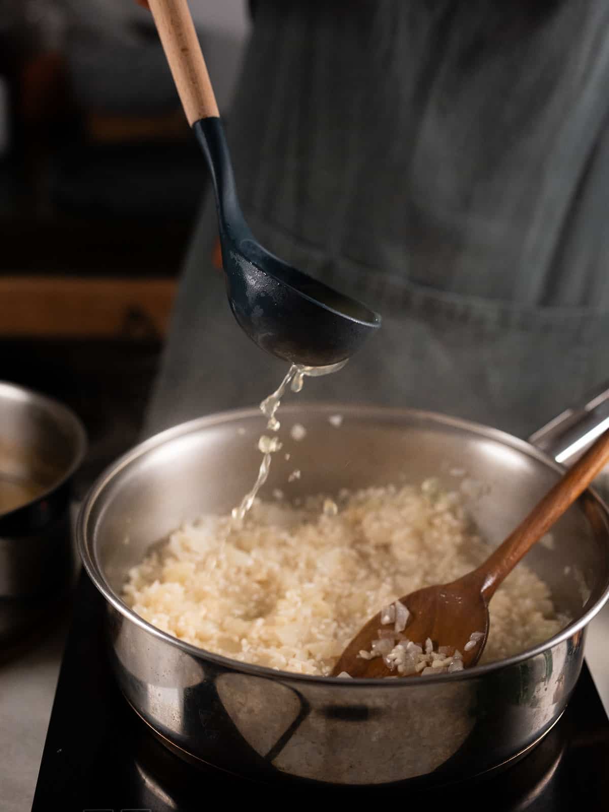 adding vegetable stock to the garlic risotto.