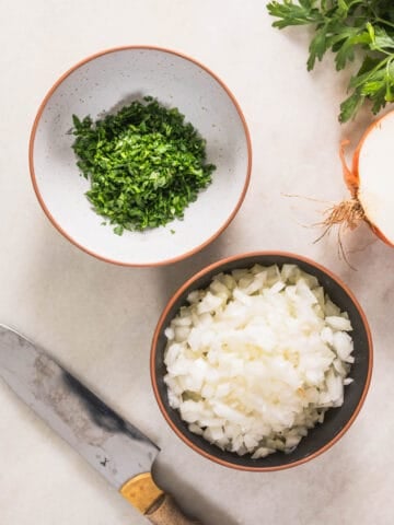 two bowls with chopped parsley and onion.