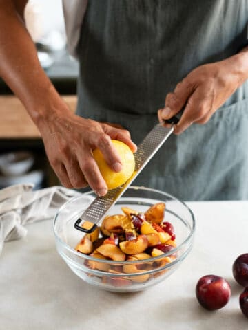 zest lemon on top of the sliced plums.