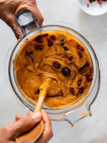 adding soaked cranberries to the sweet potato batter.