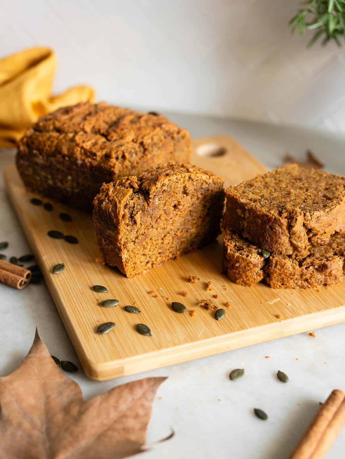 vegan pumpkin loaf cake sliced on a wooden board.