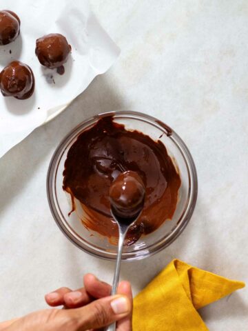 holding a pumpkin protein ball with chocolate using a spoon.