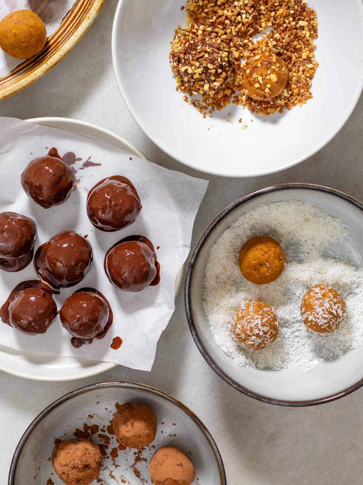 set of plates with different toppings to roll the pumpkin protein balls.