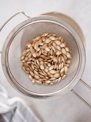 draining squash seeds using a colander.