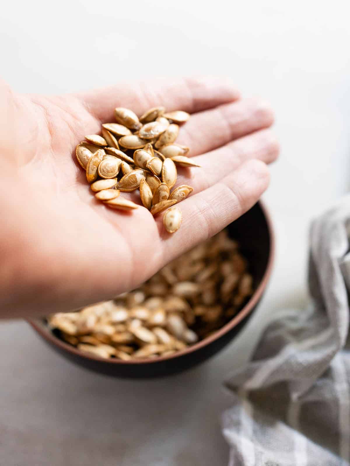 hand holding the freshly baked roasted squash seeds.