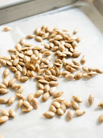 baking sheet lined with parchment paper and squash seeds.