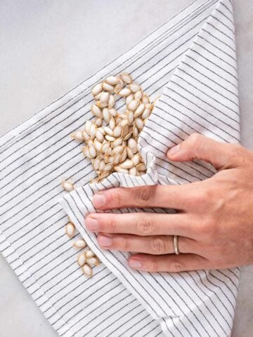 pad drying the squash seeds with a table cloth.