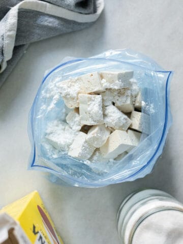 cubed tofu with cornstarch and salt on a ziplock bag.