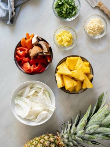 chopped vegetables, pineapple, and minced ginger, ready to start cooking in a large saucepan.