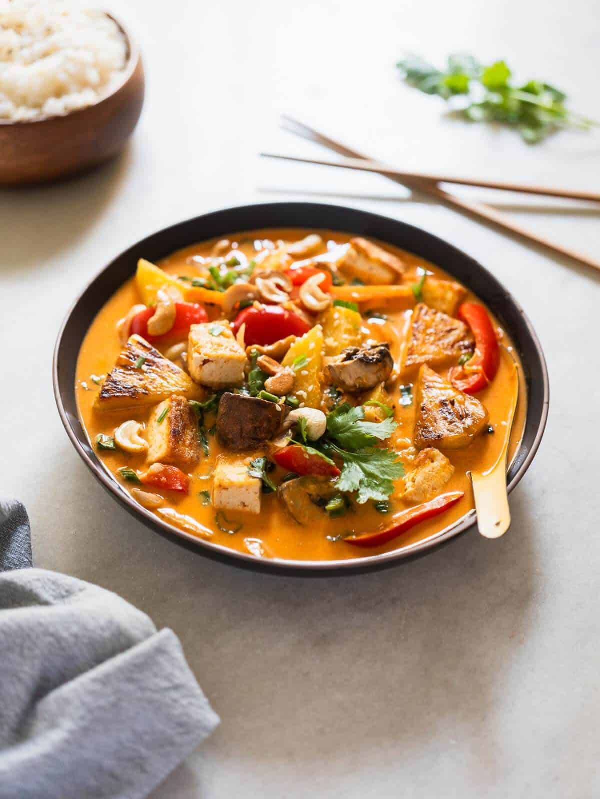 served coconut pineapple curry in a bowl with steamed Jasmine rice and chopsticks.