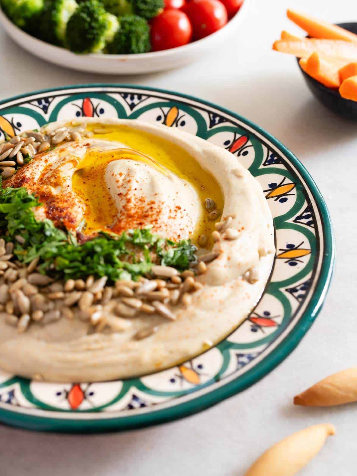 garnished plate of lentil hummus with pepitas, chopped parsley, smoked paprika and olive oil.