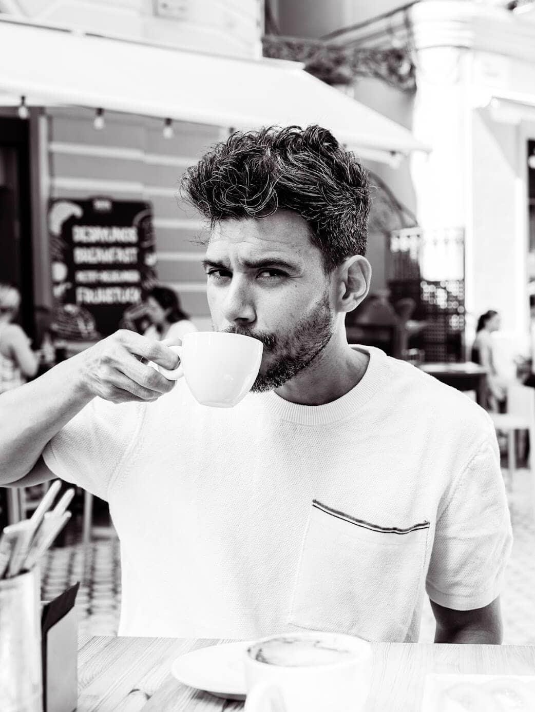 Gustavo zipping coffee in a restauran's table in Italy.