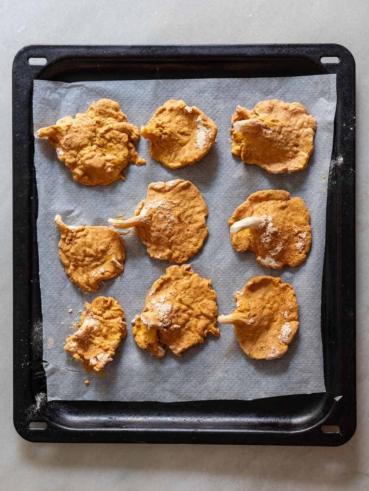 double-coated oyster mushrooms on a baking sheet lined with parchment paper.