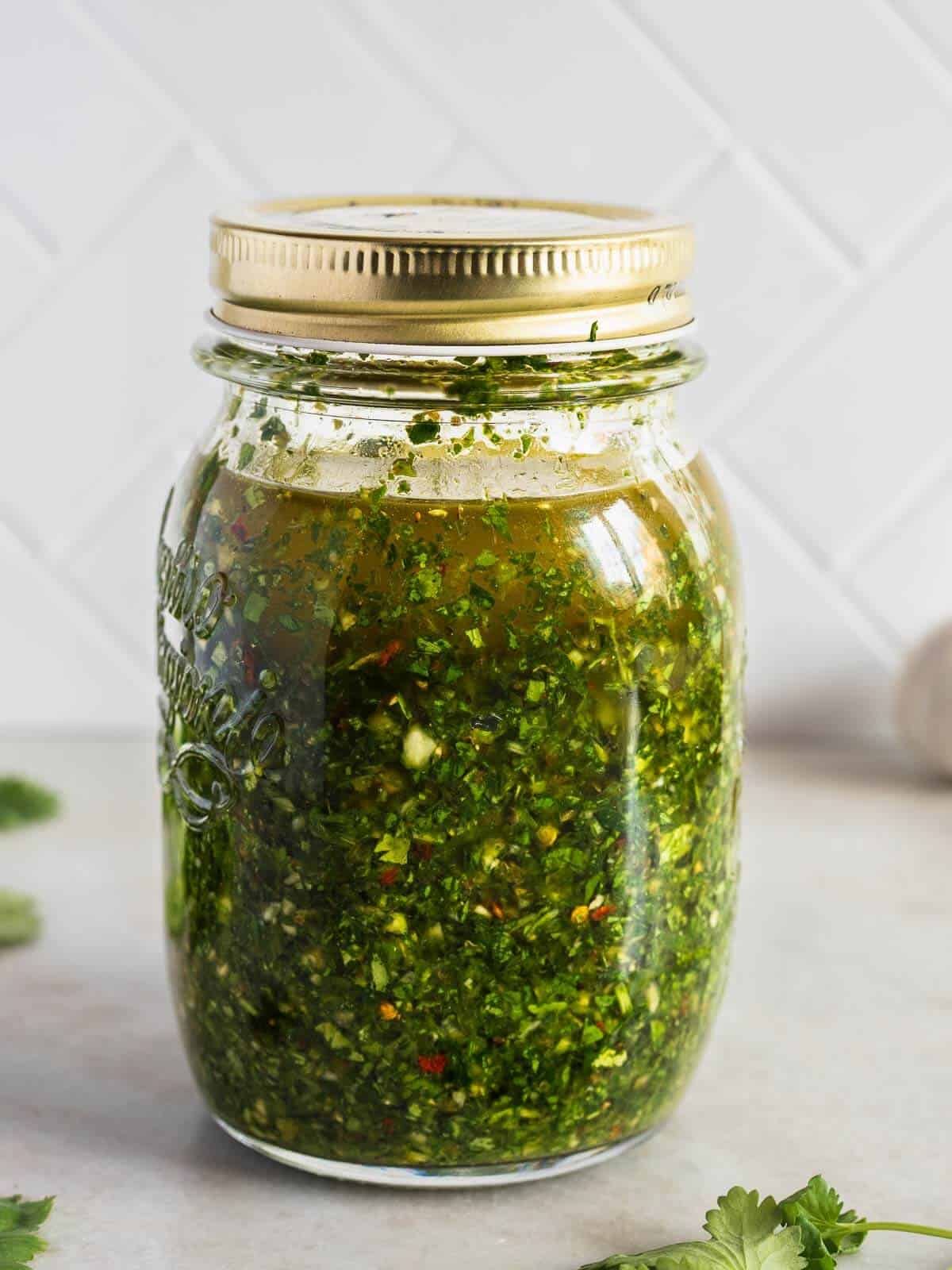 all chimichurri ingredients combined in a mason jar.