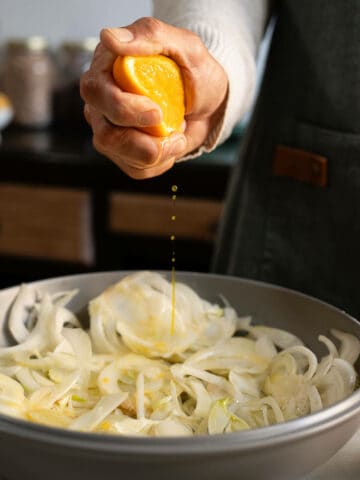 squeezing all citrus juice, orange and lemon into a bowl containing fennel.