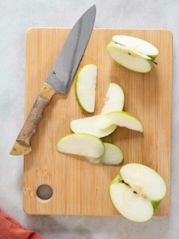 thinly sliced green apple on a chopping board.