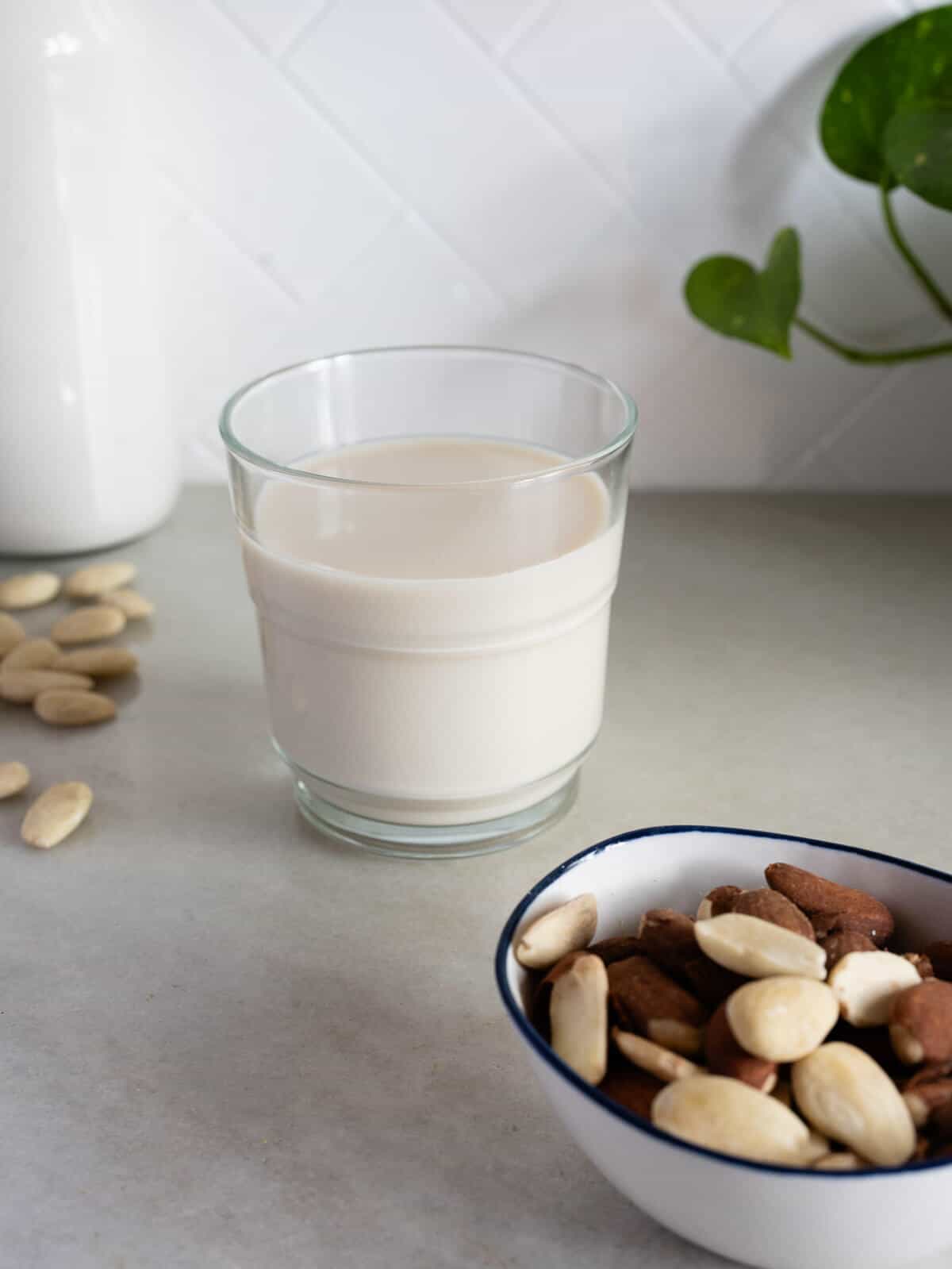 glass of almond milk next to raw almonds.