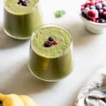two glasses of healthy green smoothie for weight loss topped with berries.