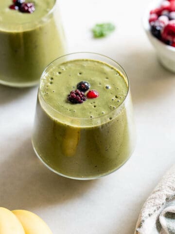 two glasses of healthy green smoothie for weight loss topped with berries.