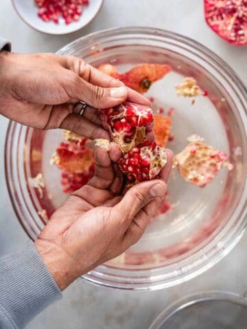 deseeding pomegranate in a bowl with water.