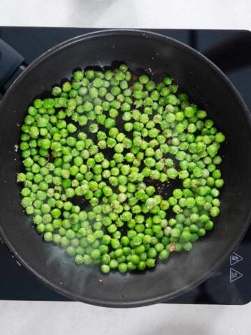 stir-frying green peas in a skillet.