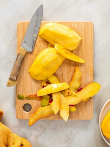 peeling ripe mango with a knife.