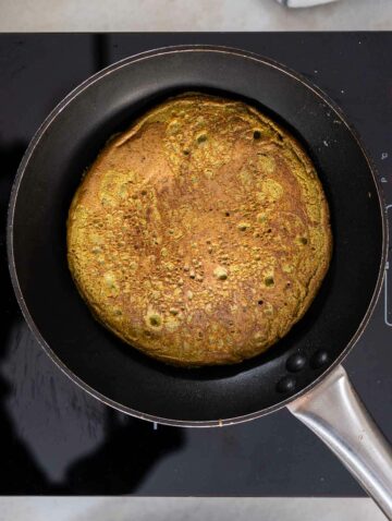 A flipped matcha pancake in a skillet, ready to be served.