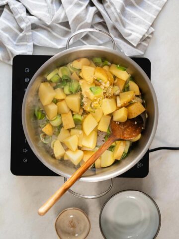 stir-frying chopped potatoes, garlic, and sliced leeks.