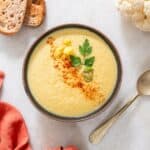 a bowl of spicy cauliflower soup garnished with cayenne pepper.