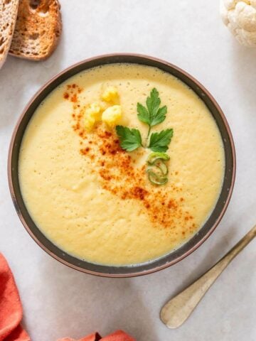 a bowl of spicy cauliflower soup garnished with cayenne pepper.
