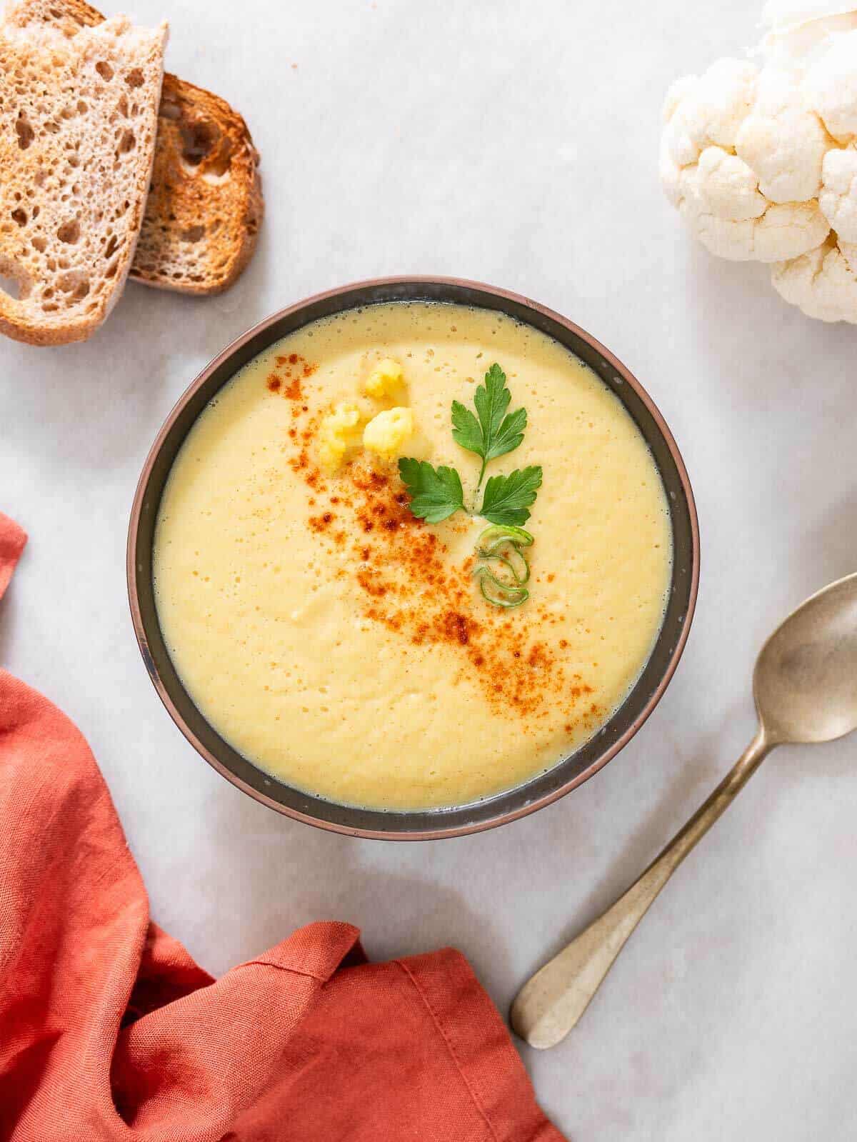 a bowl of spicy cauliflower soup garnished with cayenne pepper.