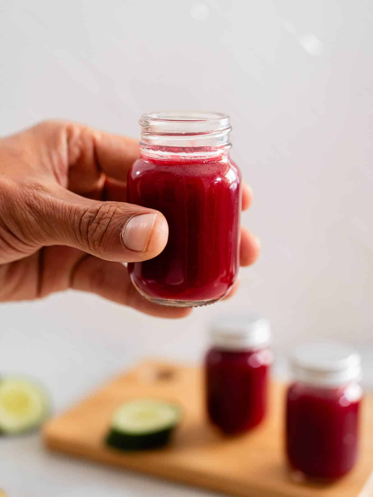 hand holding a small shot glass with juice for bloating.