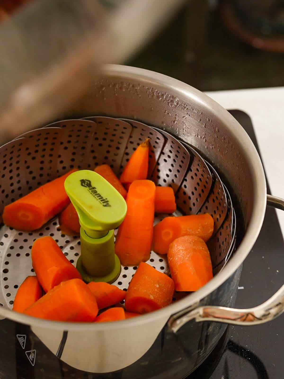 Steaming chopped carrots in pot steamer.
