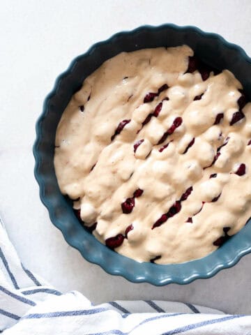 Pie Pan Filled with Cherries and Batter - Cherries arranged in a pie pan, covered with batter.