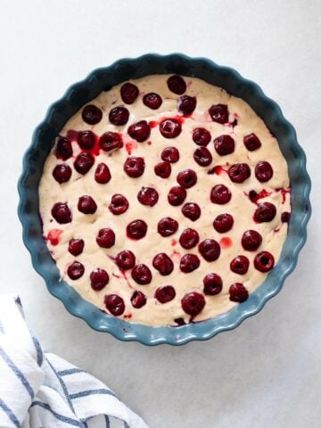 Pie Pan with Cherries on Top of Batter - Cherries placed on top of the batter in a pie pan, ready to be baked.