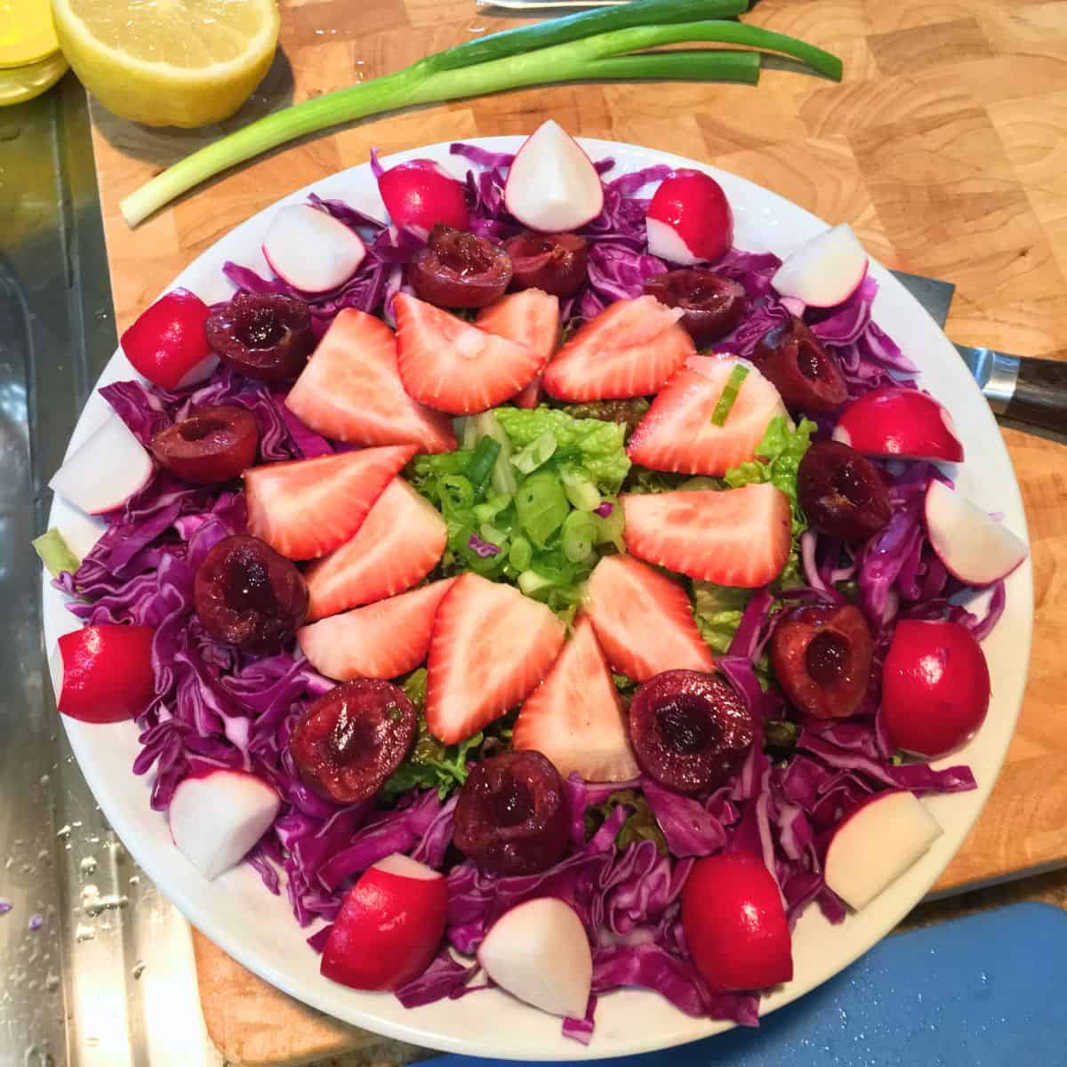 fruit and vegetable salad containing cherries, strawberries, radishes and red cabbage