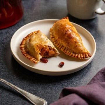 plate with two empanadas, one of which exposing the apple filling.