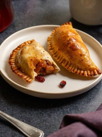 plate with two empanadas, one of which exposing the apple filling.