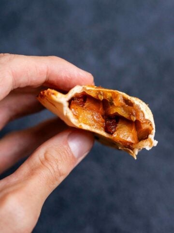 hand holding a bitten empanada.