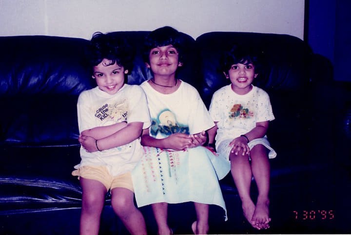 childhood picture of natasha on the extreme left, posing with her sisters, sitting on couch. dated July 1995.